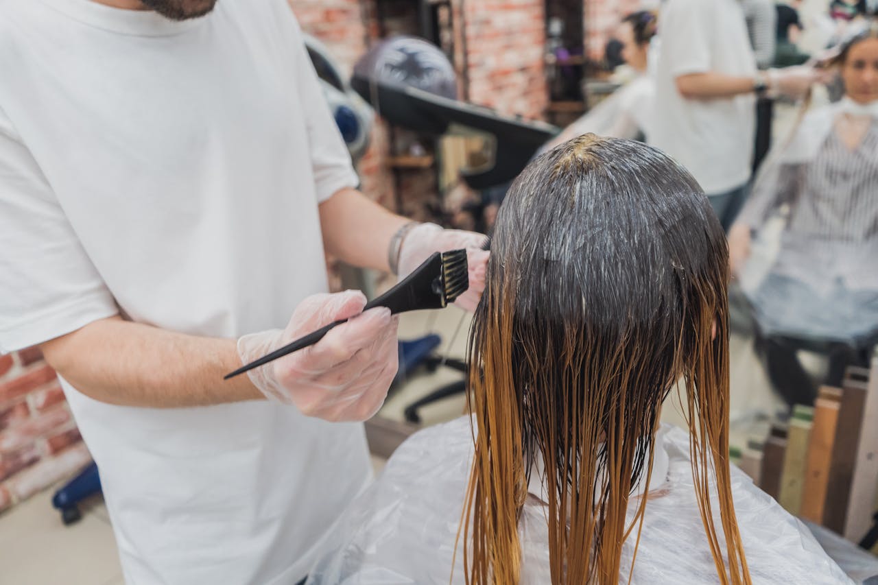 Hair coloring process in a salon, showcasing stylist applying color to clients hair.